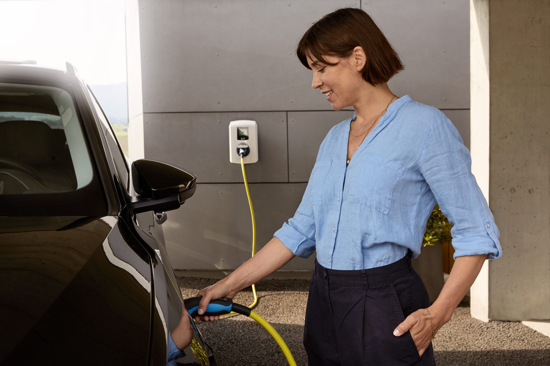 Frau, welche Ladekabel in E-Auto einsteckt